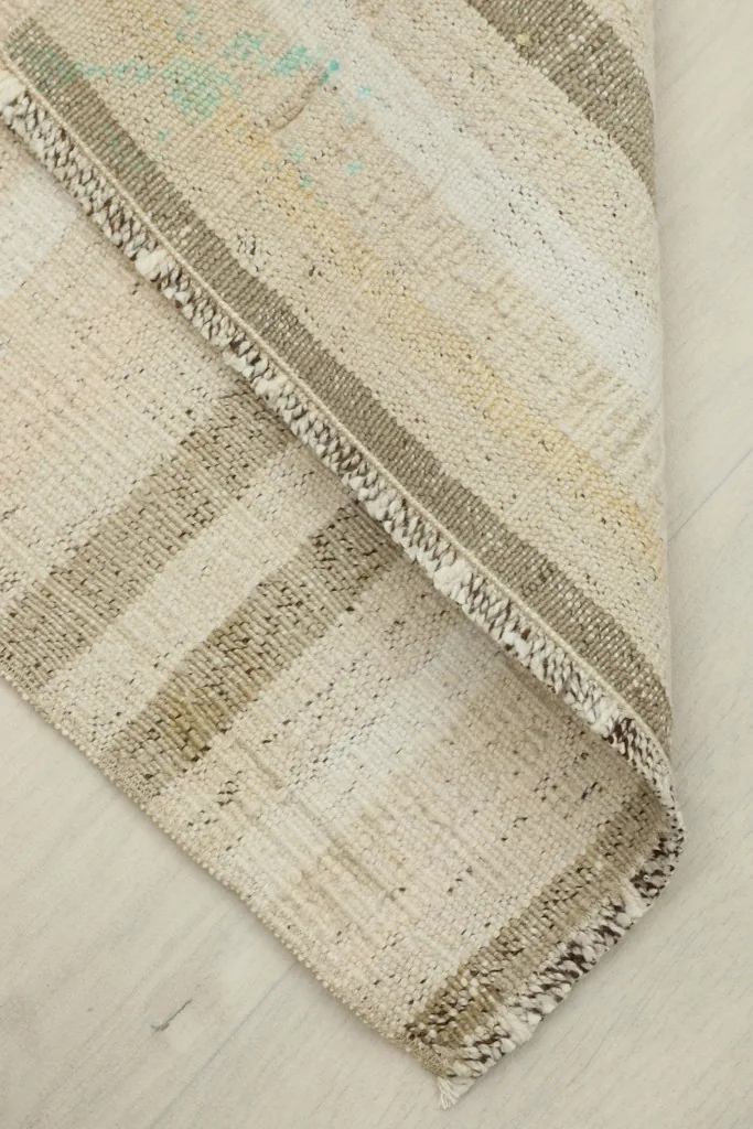View of the rug folded over, revealing the back and thickness of the hand-knotted construction