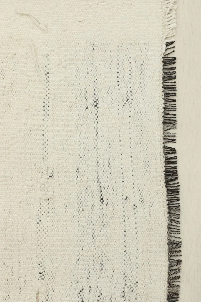 Close-up detail of the rug's edge, highlighting the hand-knotted wool pile and cotton foundation.