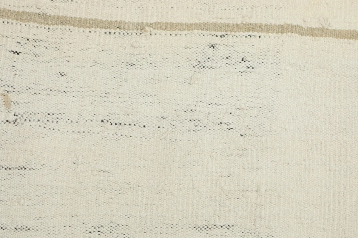 Detailed view of the ivory field with flecks of black and subtle beige tones in the vintage wool.