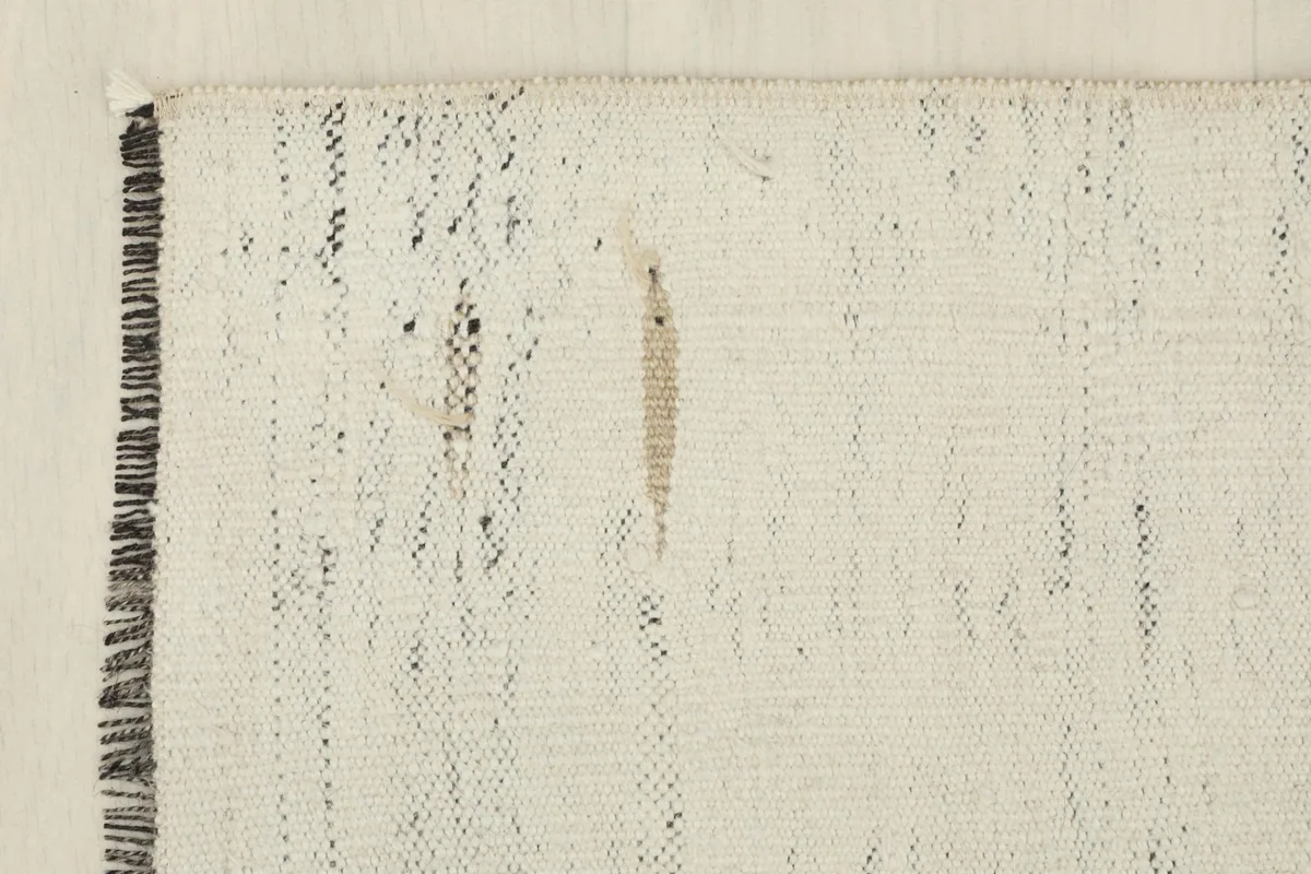 Close-up of a corner, revealing the fringes and the natural wear of the vintage rug.