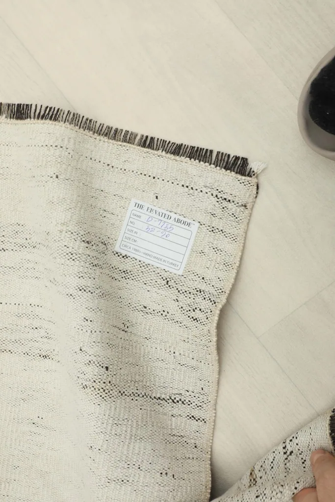 View of the rug's back, revealing the hand-knotted construction and a product label.