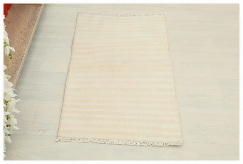 Full top view of the 1'5" x 2'7" cream and rose striped vintage Anatolian doormat on a white background.