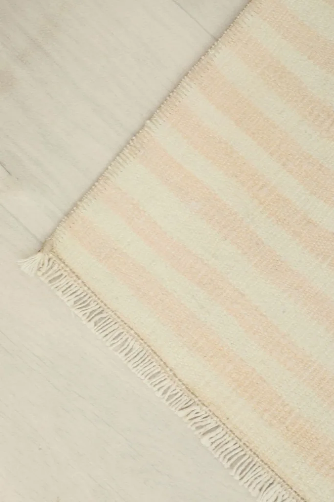 Corner view of the rug, illustrating its rectangular shape and the light wear consistent with its vintage age.