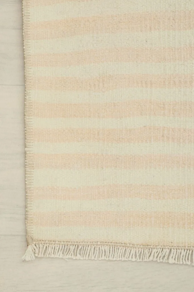 Detail shot of the rug's edge, showcasing the finished border and the short, natural fringes.