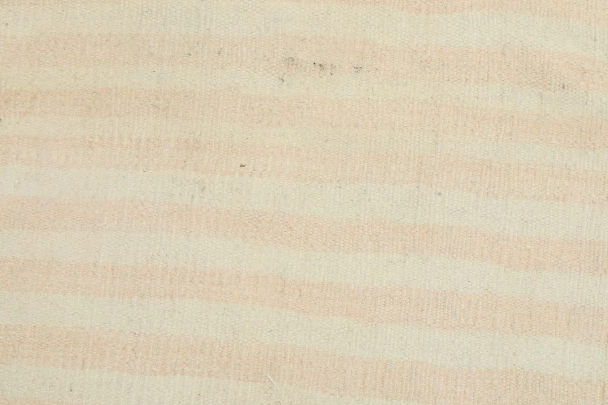 Macro view of the low wool pile, showing the texture and the subtle color blend of cream and rose stripes.