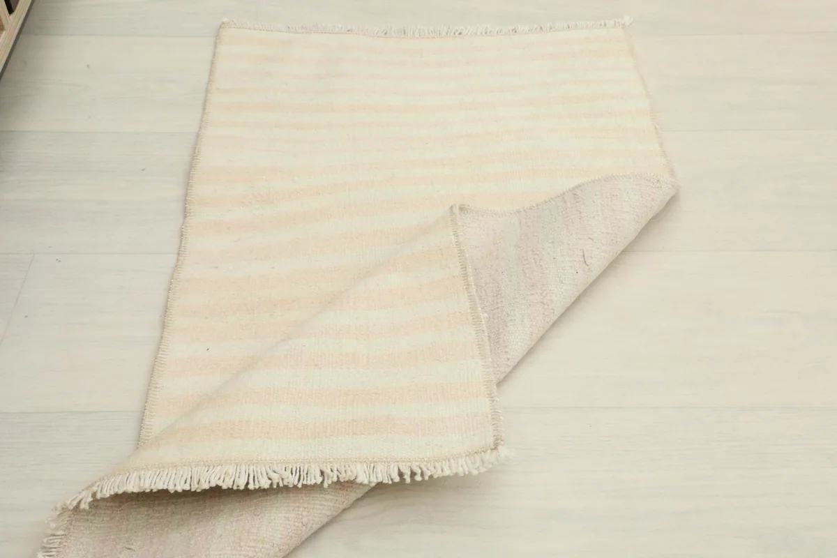 The rug partially folded, displaying both the top surface with its stripes and the reverse side.