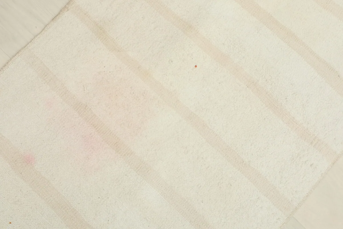 Detailed view of the wool pile and the subtle beige stripes with faint rose discoloration.