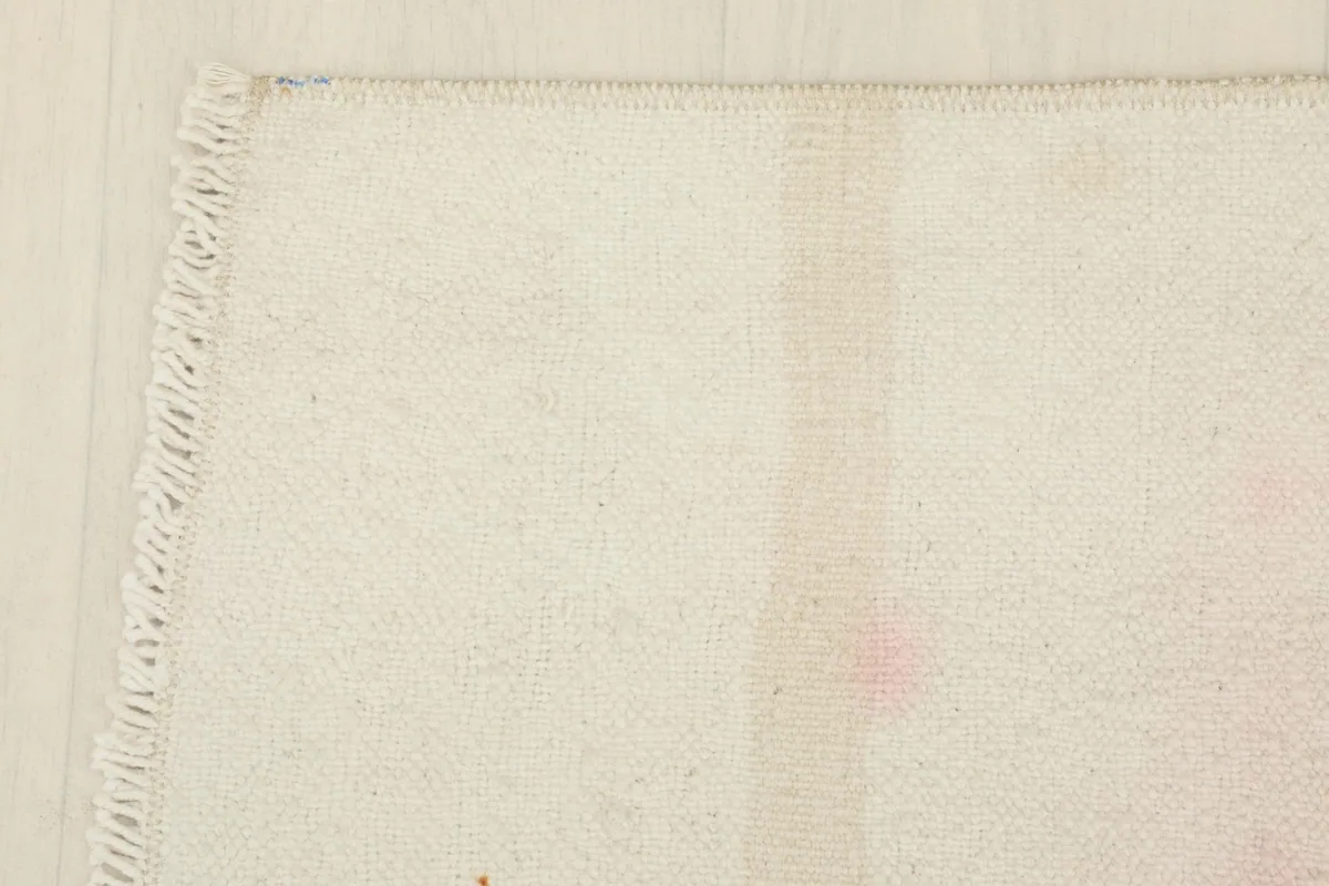 Corner detail showing the finished edge and a glimpse of the hand-knotted fringe.