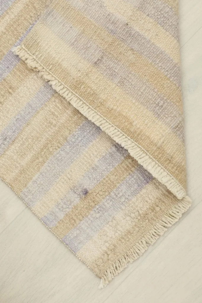 The rug partially folded, revealing the thickness and flexibility of the vintage wool material.