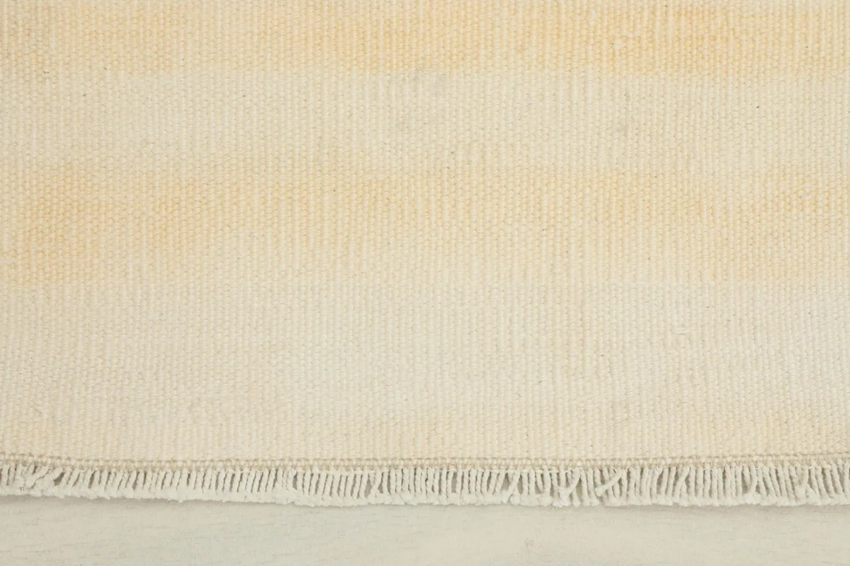 Close-up detail of the cream and tan stripes and the short fringe along one end of the hand-knotted doormat.