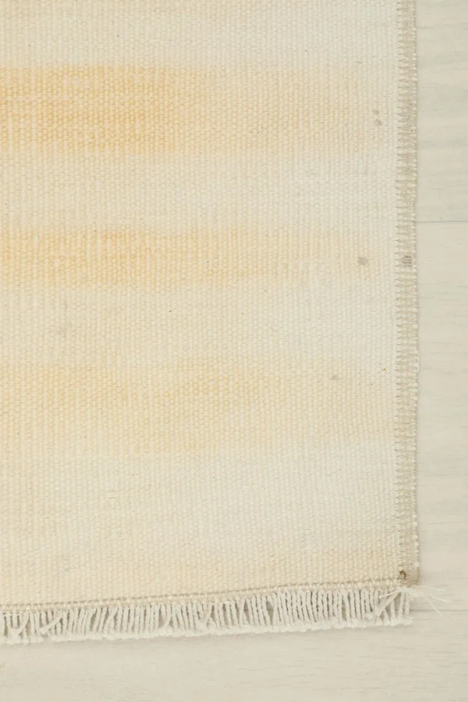 Close-up of the short fringe and the tightly finished edge of the vintage Anatolian doormat.