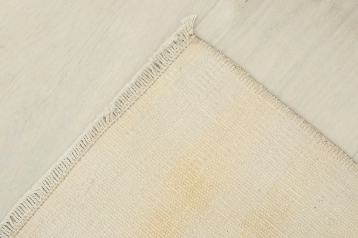 Corner view showing the reverse side of the rug, revealing the cotton foundation and hand-knotted construction.