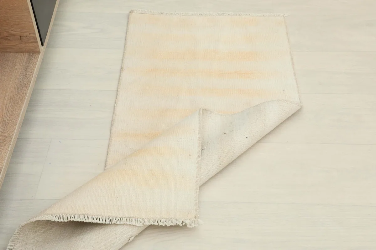 The rug partially folded, displaying both the cream and tan striped pile and the back of the rug.