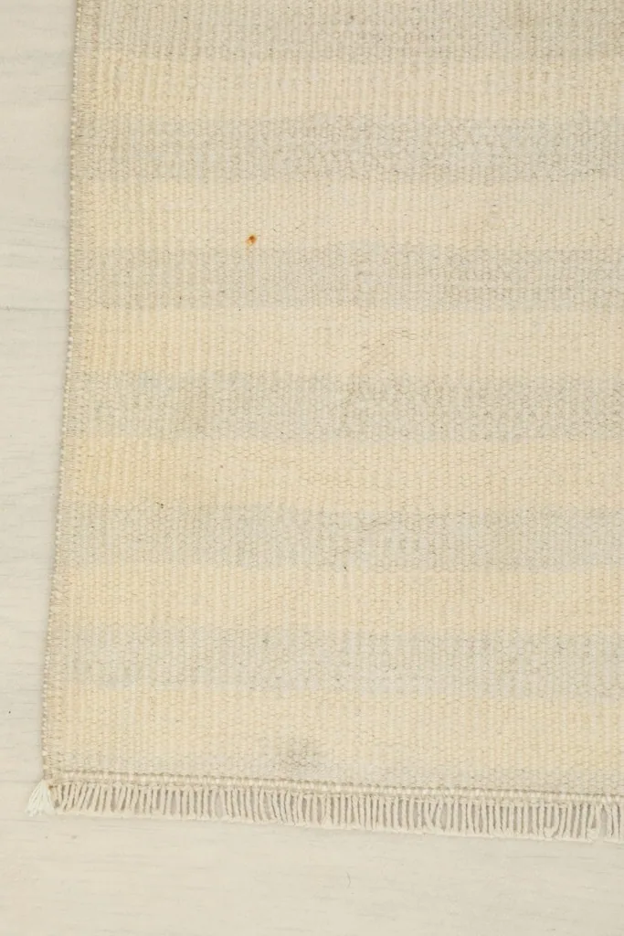 Close-up of the rug's edge, showing the tight weave and subtle gray tones