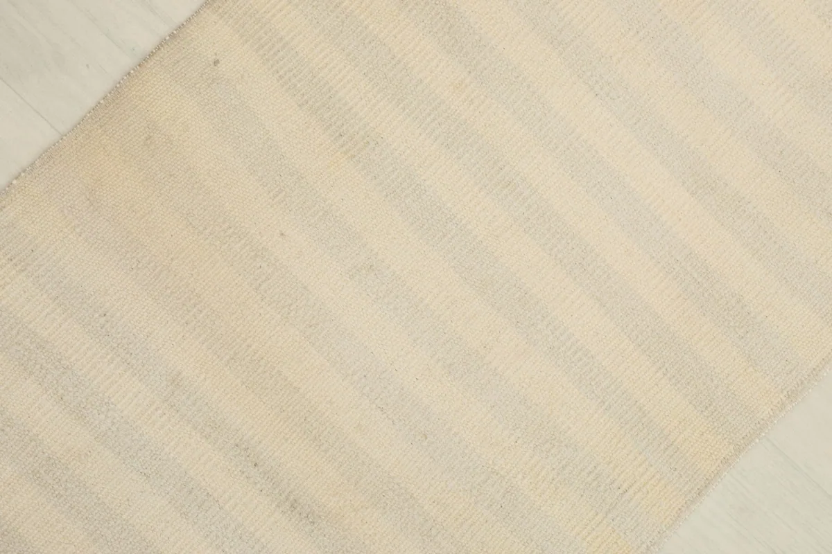 Overhead view showing the texture and subtle color variations of the ivory rug