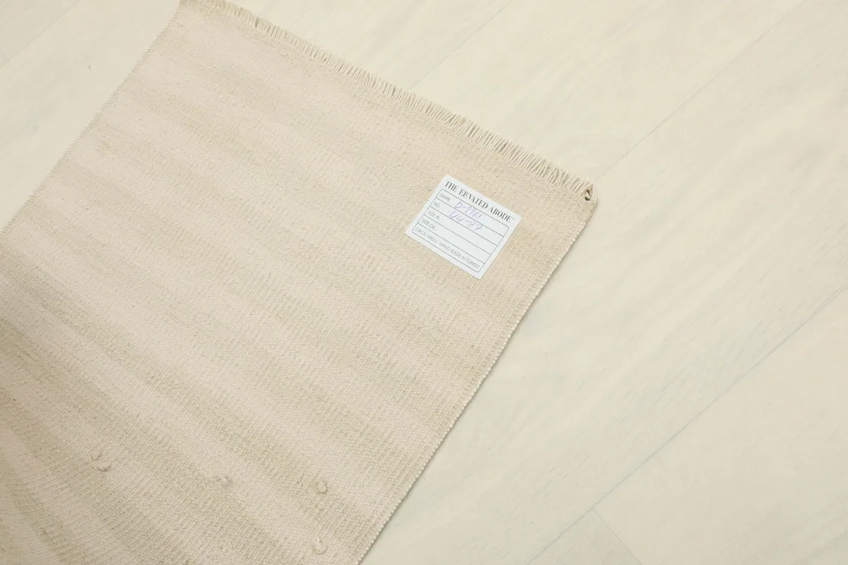 Angled view of the rug with a label on the reverse side, showing its origin