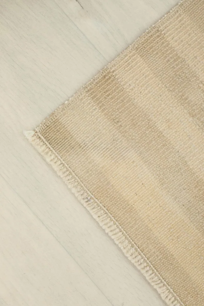 Corner view of the rug, highlighting the finished edge and the tight weave of the wool pile.