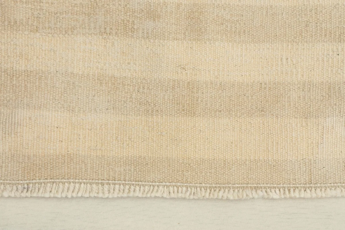 Close-up detail of the hand-knotted wool pile and the striped pattern, showing the fringe edge.