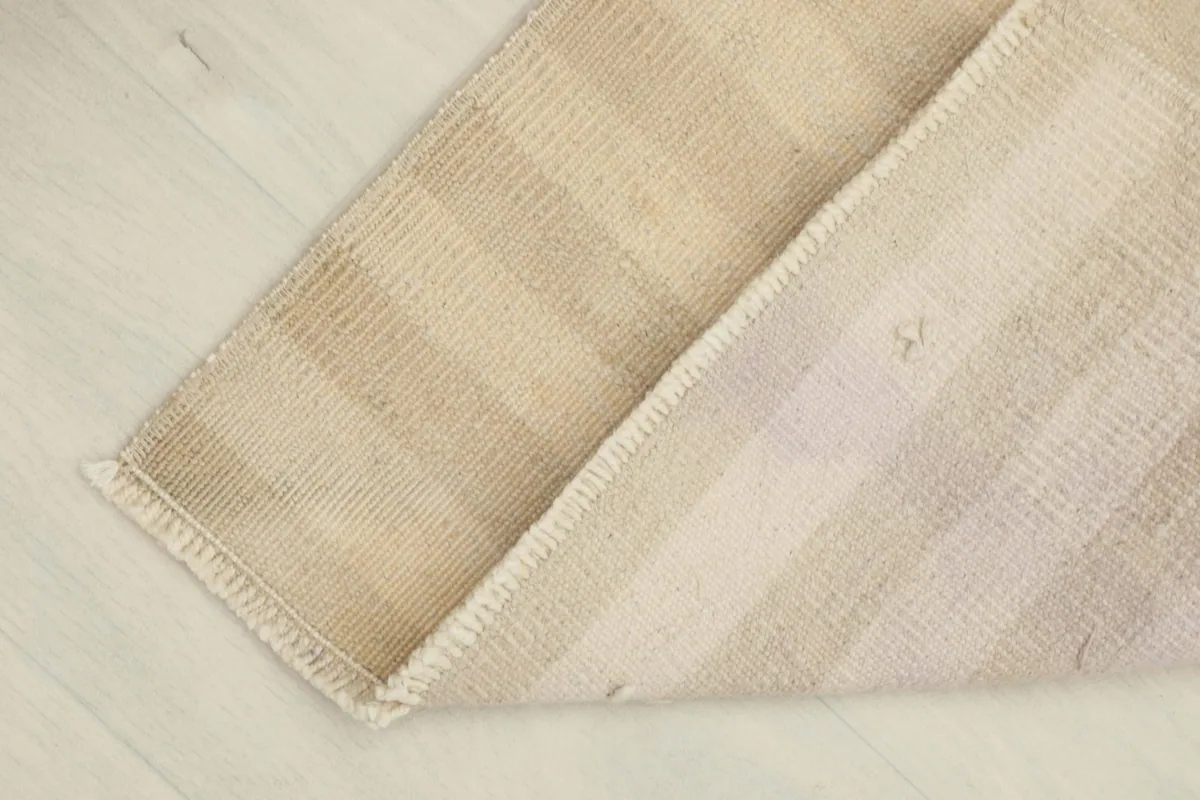 View of the rug turned over, showing the cotton foundation and the reverse side of the hand-knotted construction.