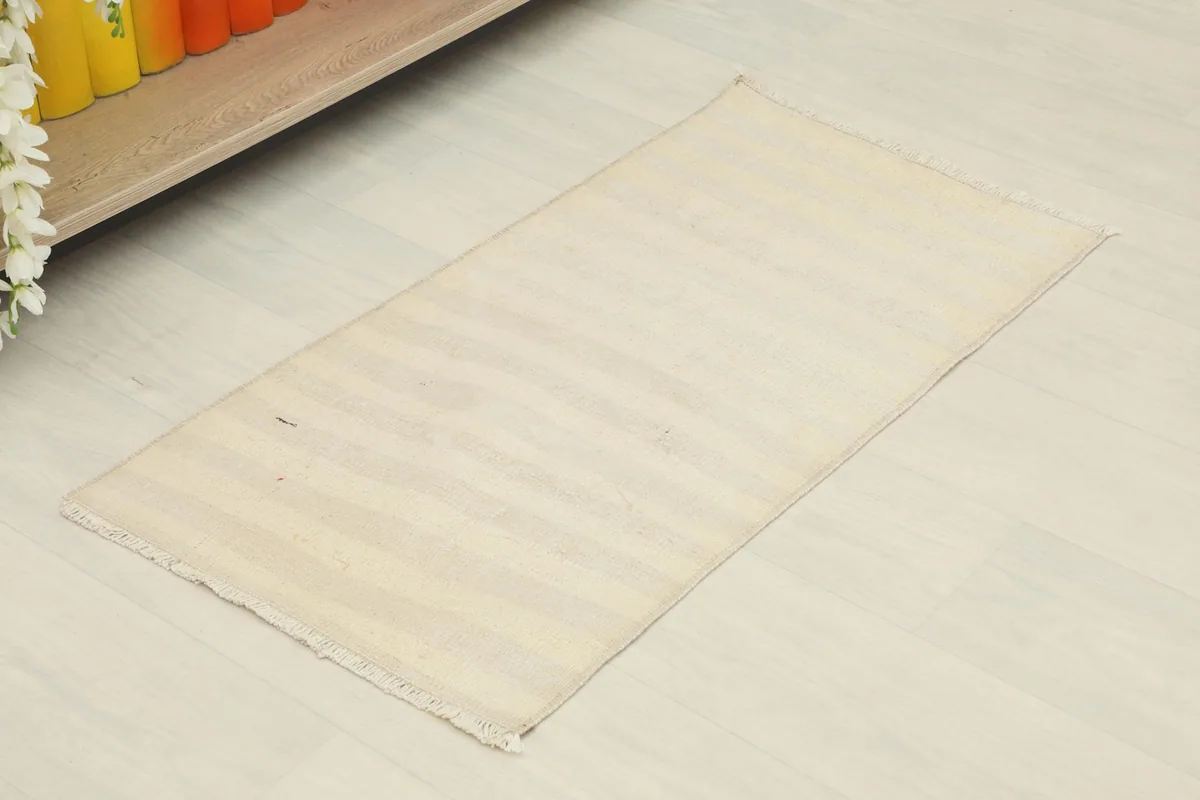 Angled view of the cream and beige striped rug, showcasing its rectangular shape and subtle variations.
