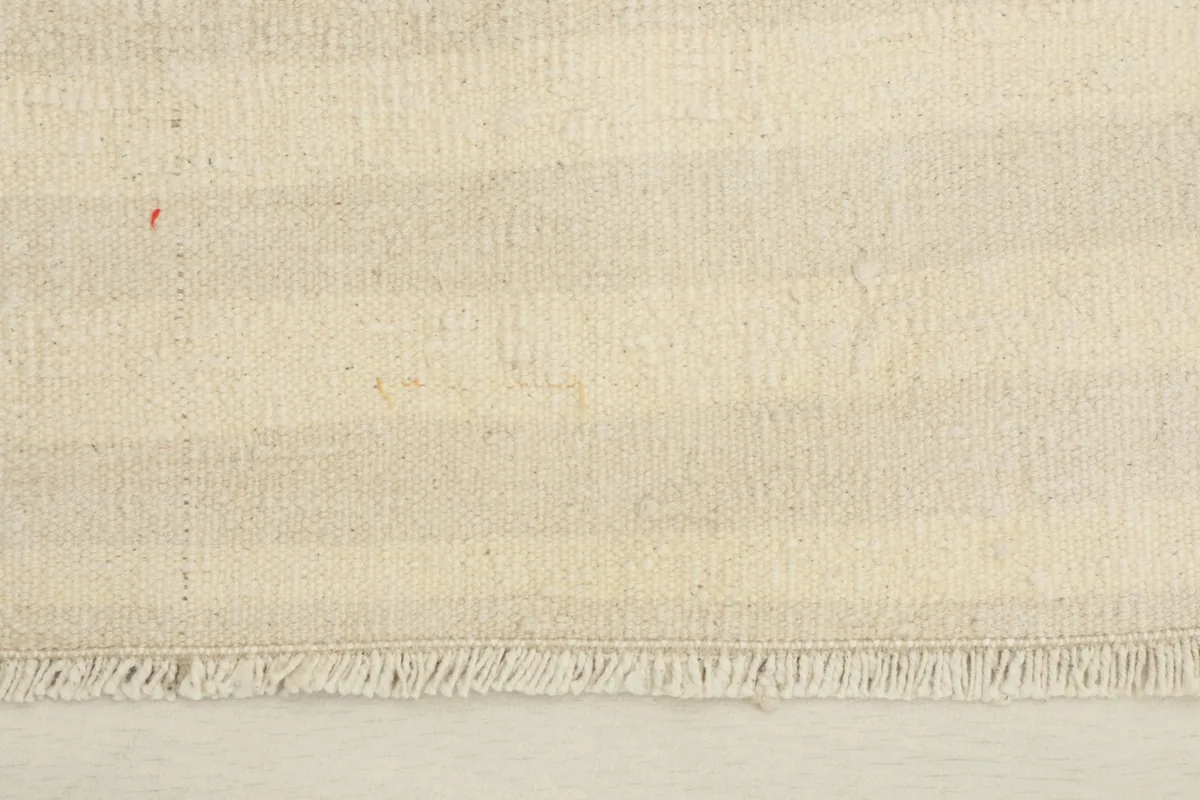 Close-up detail of the hand-knotted wool pile and the striped pattern, showing fringe at one end.