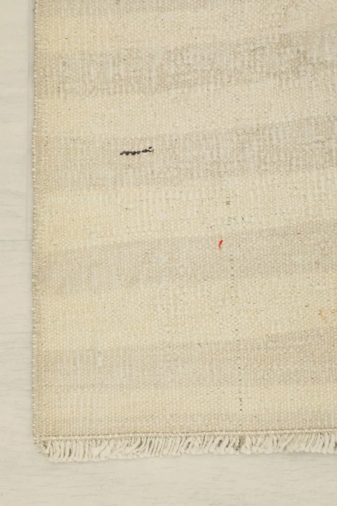 Detail of the rug's edge and fringe, showing the hand-finished quality and slight patina.