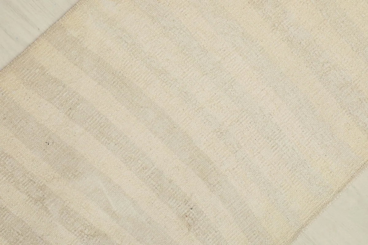 Overhead view focusing on the texture and striped pattern across the cream and beige rug.