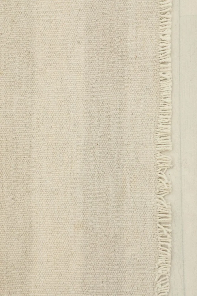 Close-up detail of the hand-knotted wool pile and fringe of the rug