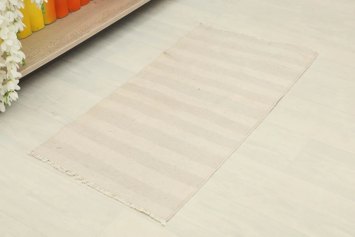 Overhead view of the beige and cream striped rug on a light floor