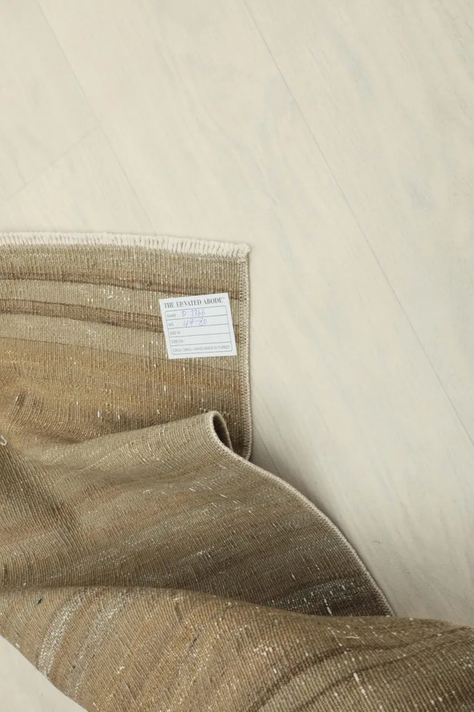 View of the back of the rug, showing the cotton foundation and a product label.