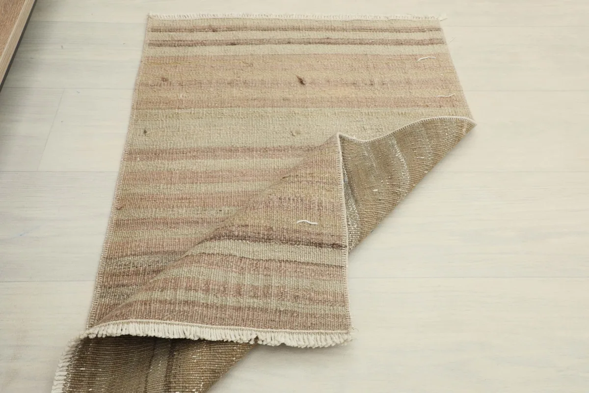 Partially folded rug, demonstrating its pliable nature and the overall striped design.