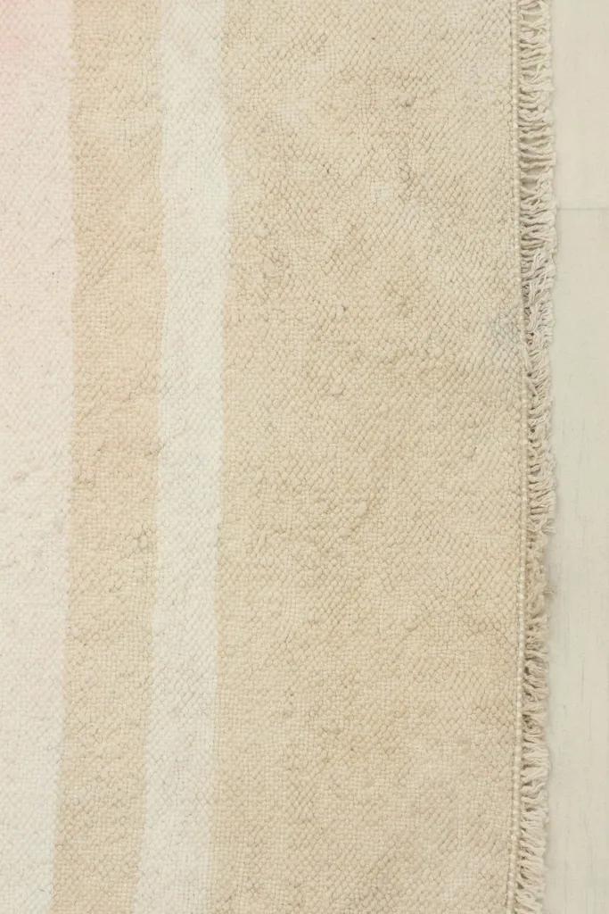 Close-up detail of the hand-knotted wool pile, showing the texture and fringe along one edge.