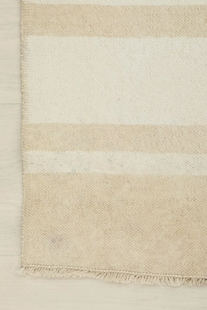 Close-up of the rug's corner, highlighting the striped pattern and the short fringe.