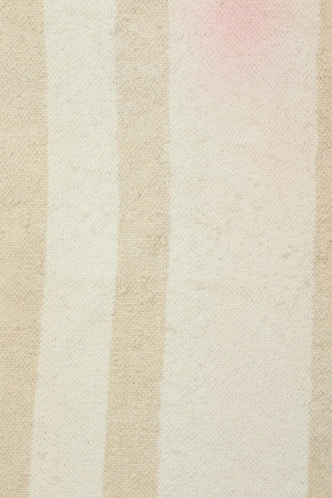 Detailed view of the low wool pile, showing the subtle color shifts within the stripes and some wear.