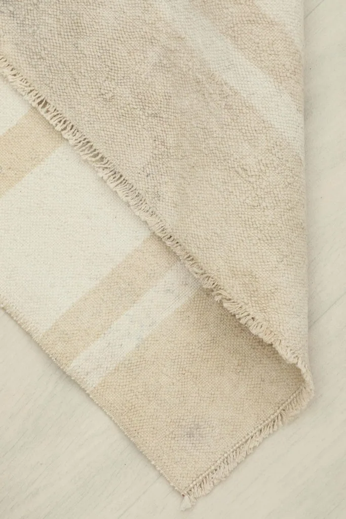 View of the rug folded back, revealing the underside and the hand-knotted cotton foundation.