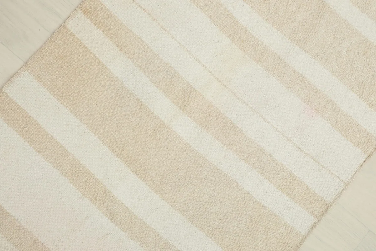 Overhead view of a section of the rug, emphasizing the varying beige and cream stripes.