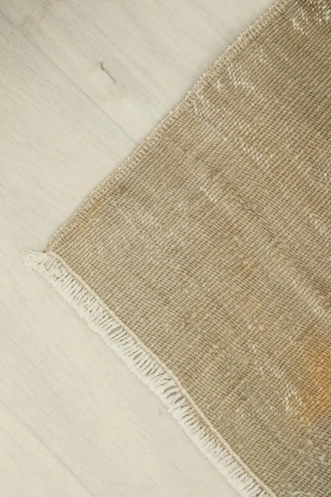 Angled view focusing on one corner of the rug, showing the fringe and the overall flat lay.