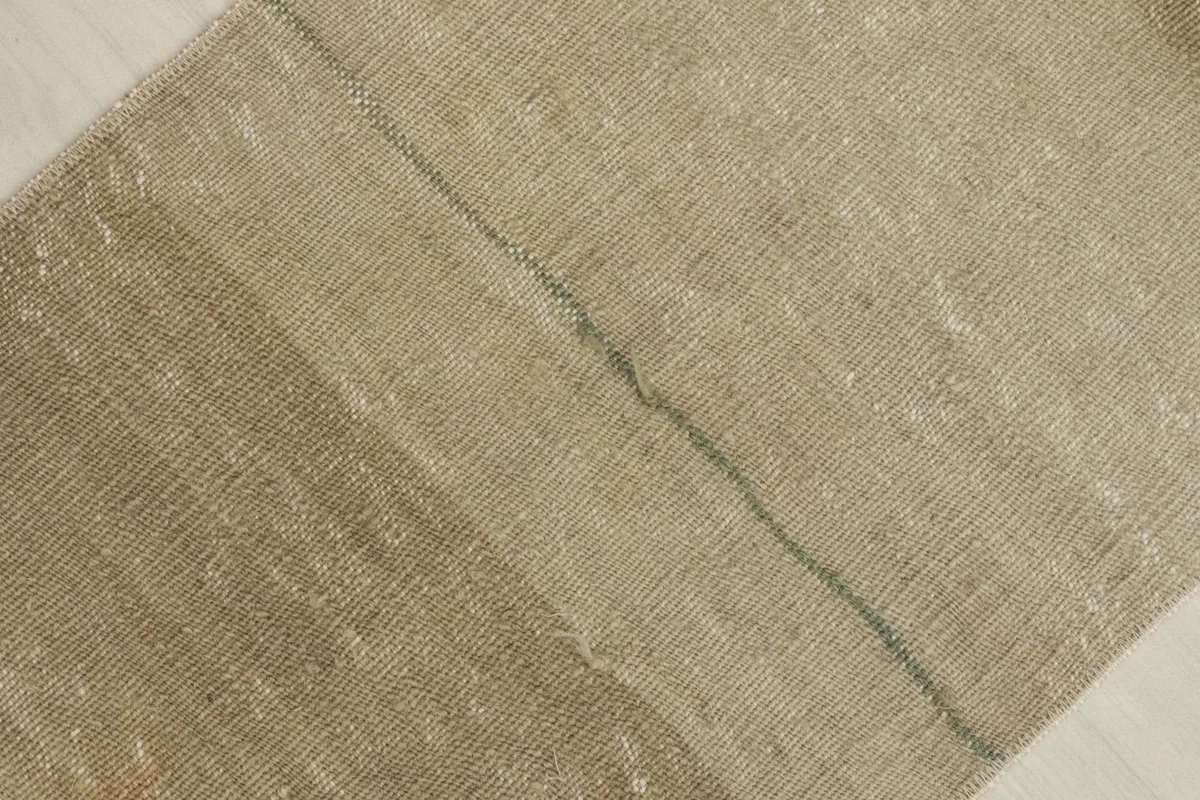 Detail shot highlighting a subtle green thread line and the horizontal color variation in the rug's weave.