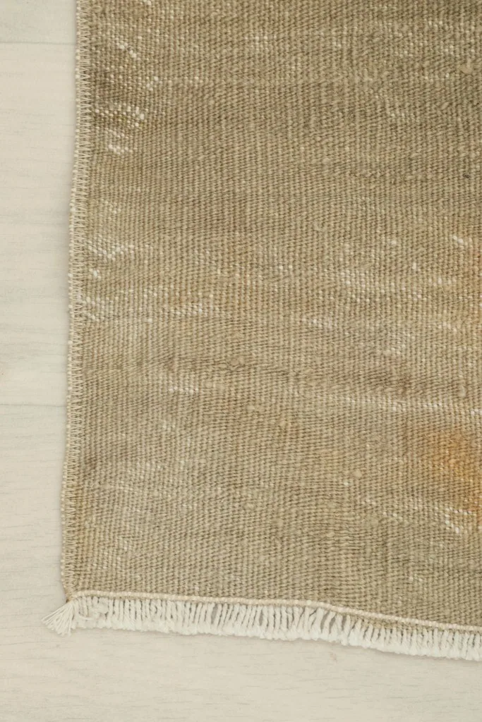Detail of the rug's edge and fringe, showcasing the hand-knotted construction.