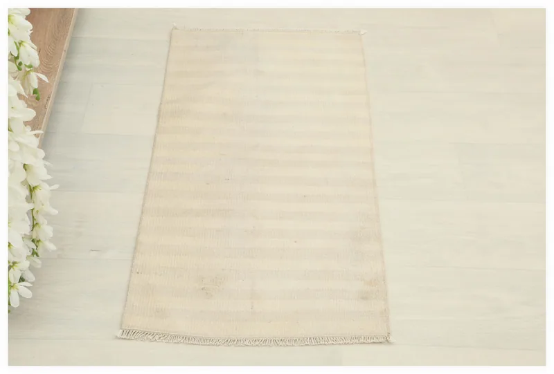 Full top view of the 1'5" x 2'10" ivory and beige striped vintage Anatolian doormat on a white background.