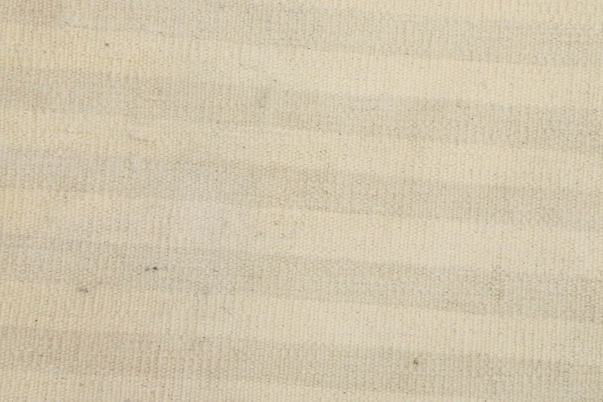 Very close-up of the low wool pile, showing the texture and the subtle horizontal stripe pattern in ivory and beige.
