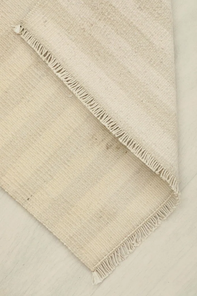 The rug folded to show its flexibility and the consistent weave of the ivory and beige stripes.