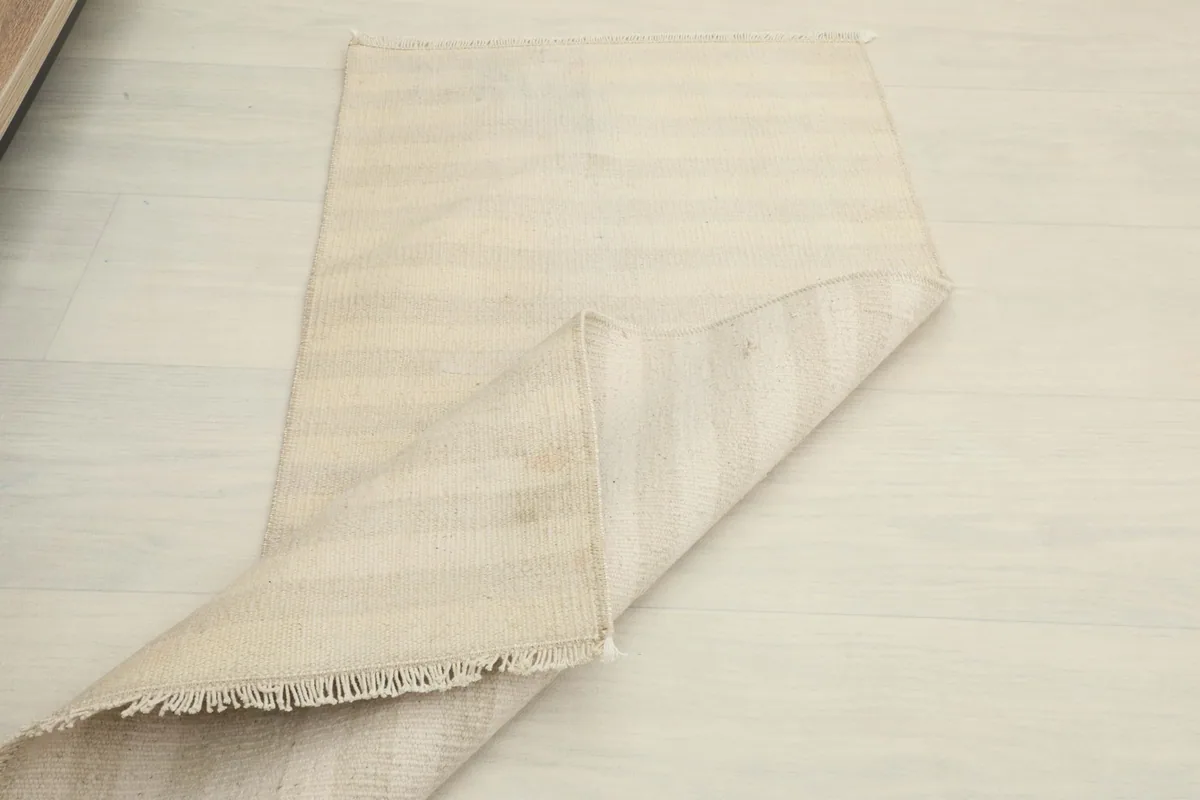 Another view of the rug partially folded, emphasizing its compact size and the soft wool material.