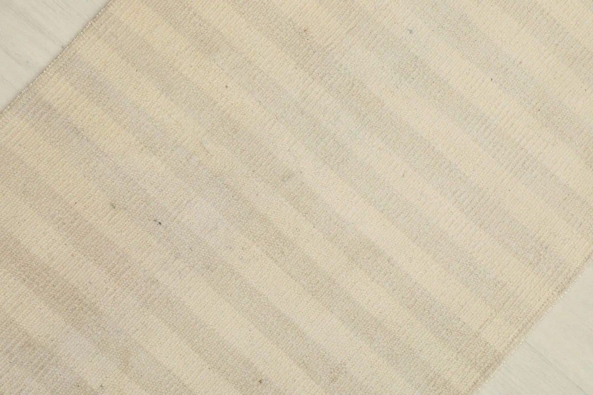 Overhead view from an angle, highlighting the full pattern of ivory and beige stripes across the vintage rug.
