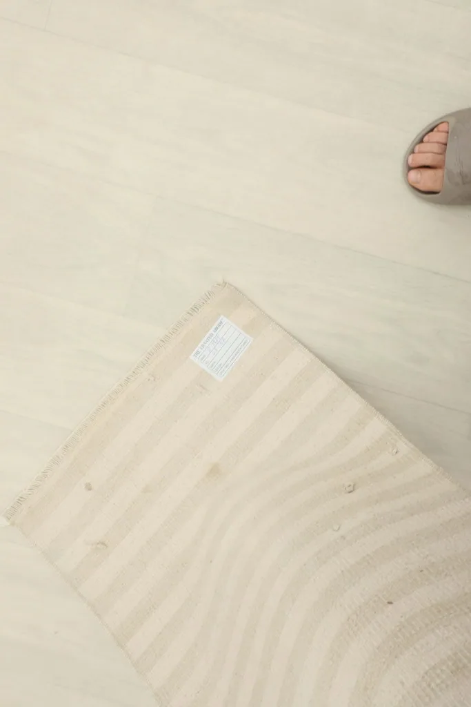 Top-down view of the rug with a person's foot nearby, providing a sense of scale for the 1'5" x 2'10" doormat.
