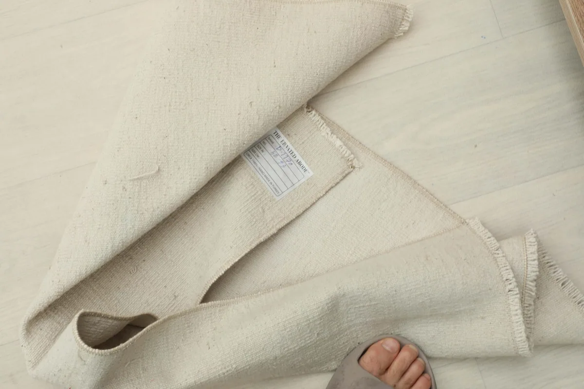 The rug folded to reveal a small label on the back, with a foot nearby for scale