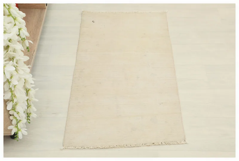 Full top view of the ivory beige hand-knotted vintage Anatolian doormat on a white background.