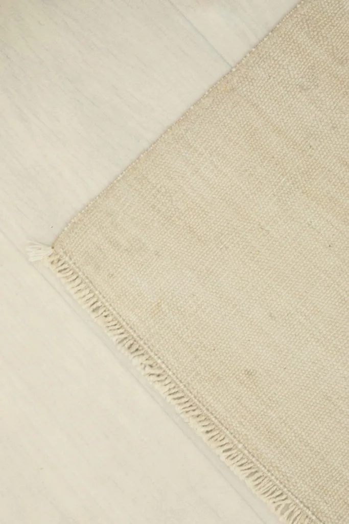 Corner view of the rug laid flat, emphasizing its simple design and clean lines.