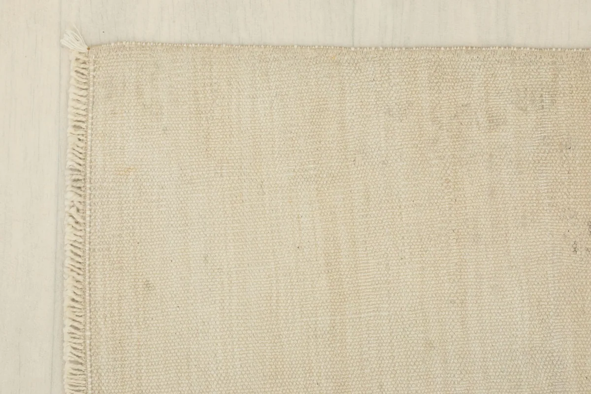 Corner detail of the rug, showing the neat edge finish and short, natural fringe.