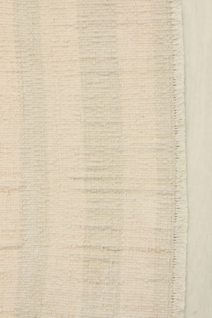 Close-up detail of the hand-knotted wool pile and subtle horizontal stripes in ivory and beige.